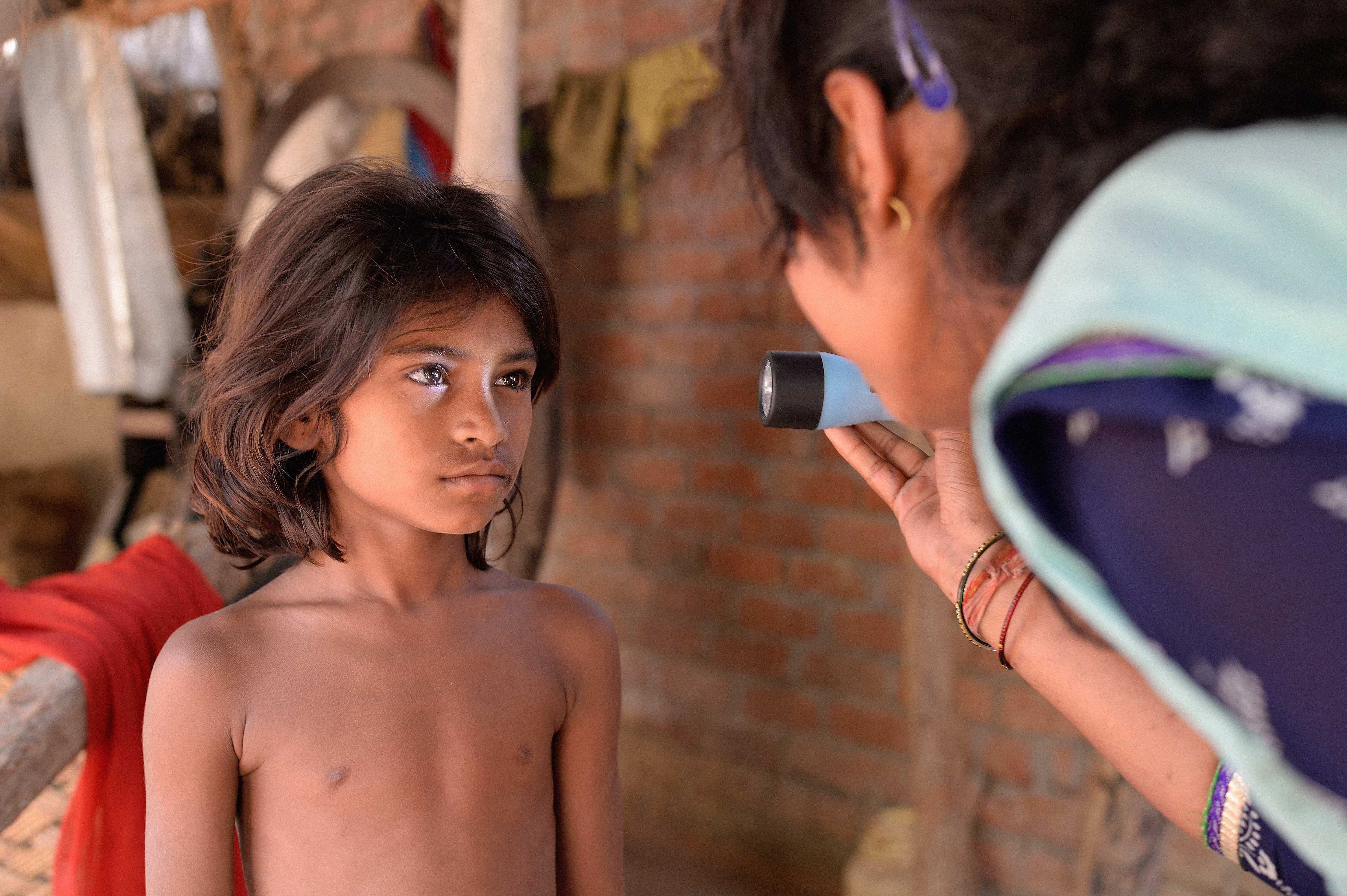 Indian boy having his eyes examined by a community health worker