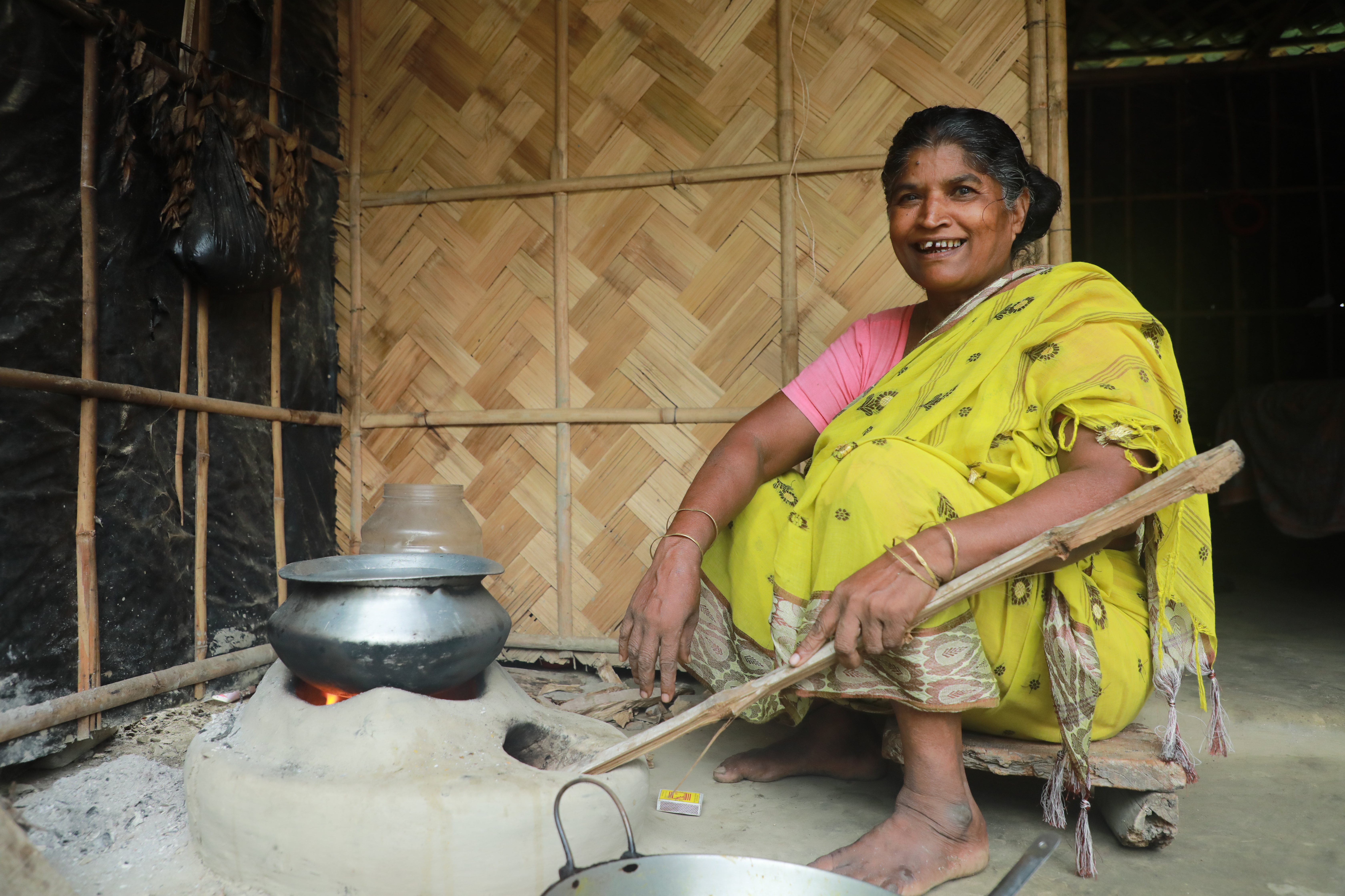 Savitri in her kitchen sitting by a stove made of mud.
