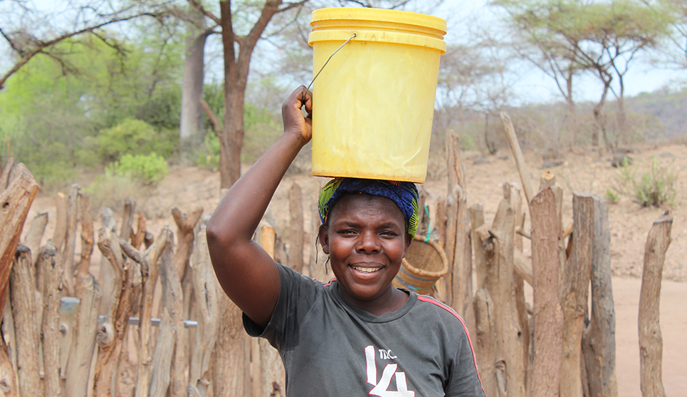 Woman holding bucket of water over her head, in Ghana
