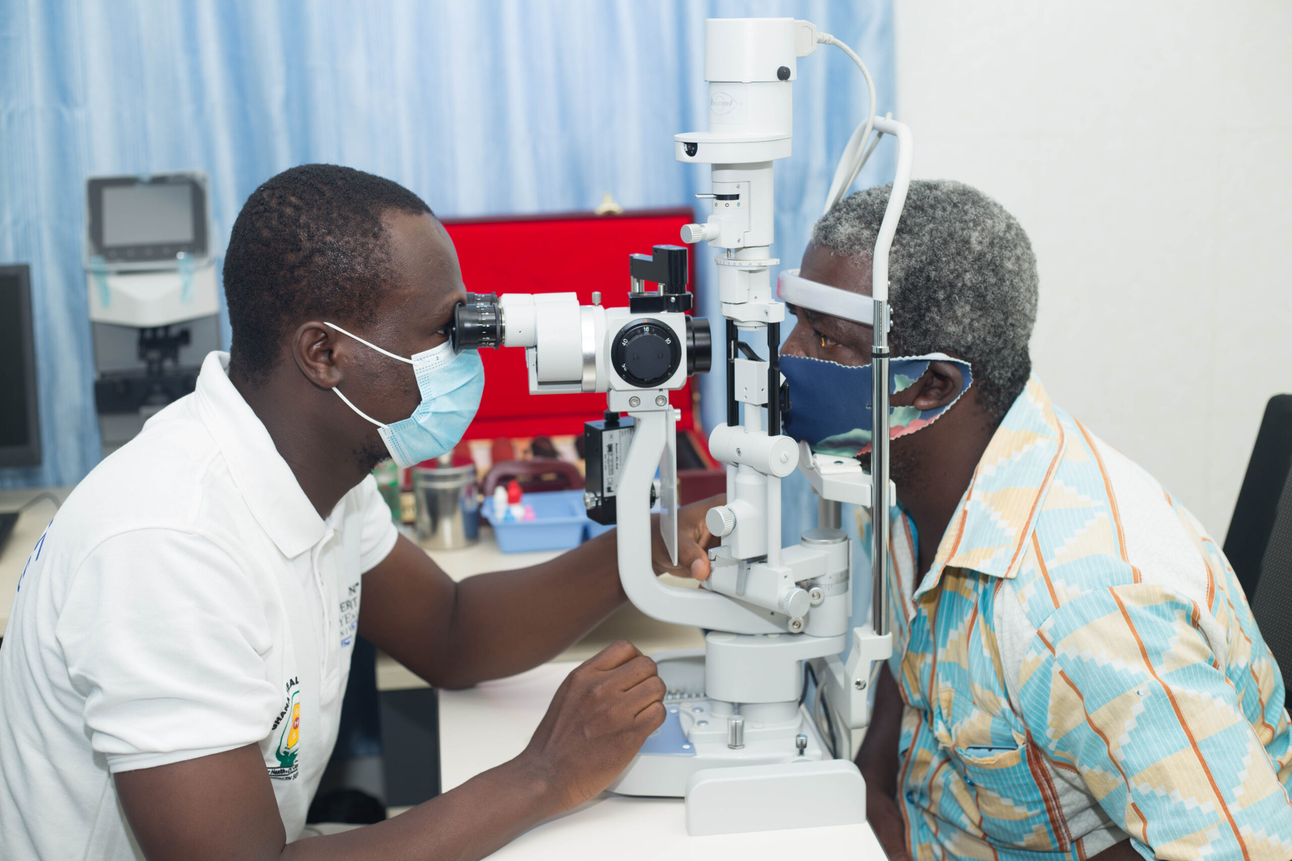 Care worker performing an eye examination for male patient.