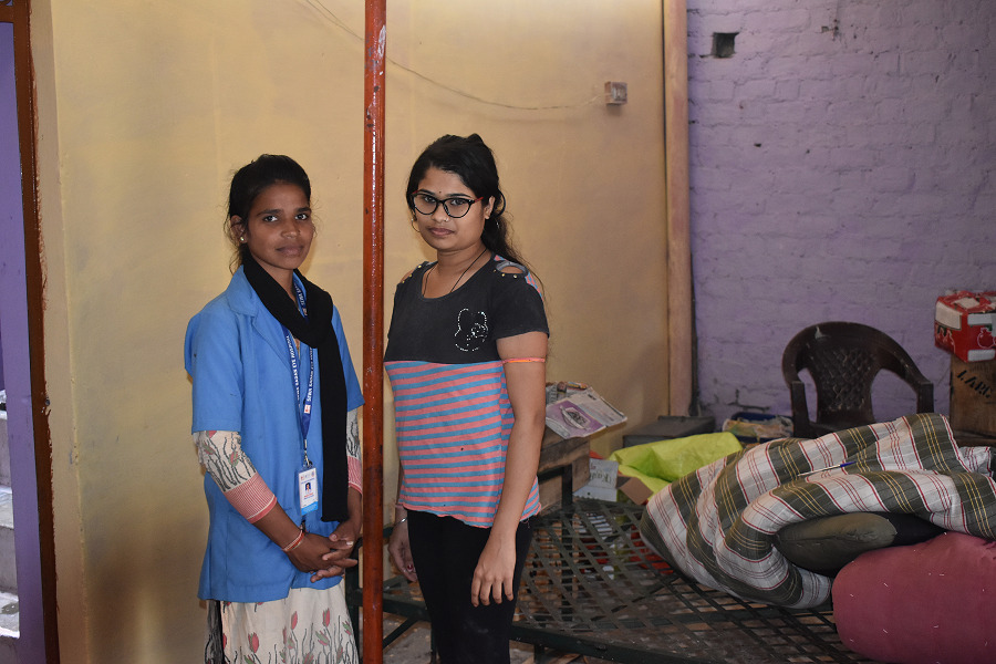A young woman, wearing eyeglasses, poses for a photo with a community health worker.