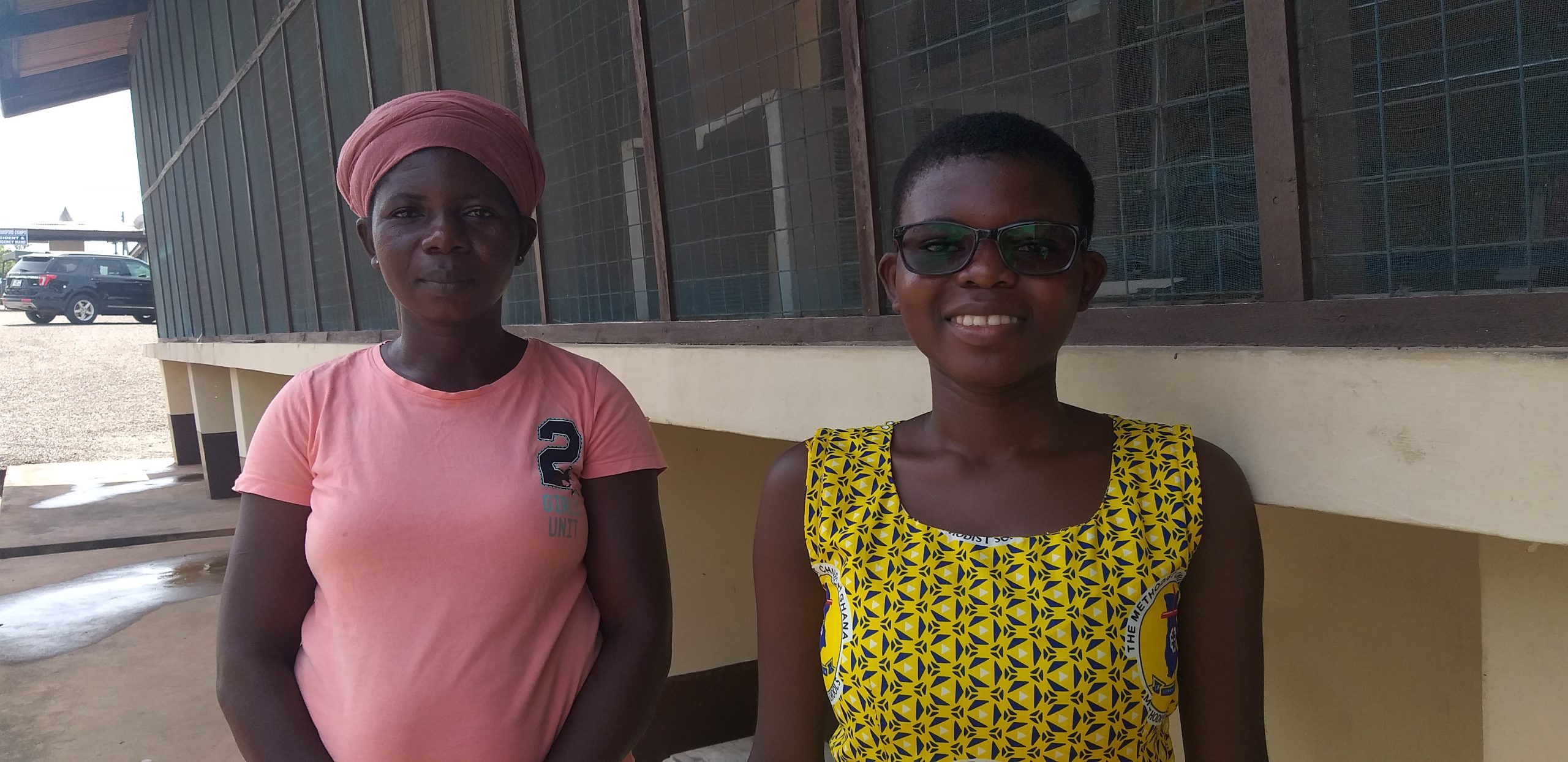A teenager, wearing eyeglasses, stands with her mom for a photo