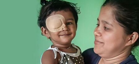 A mother smiles at her daughter who is wearing an eye patch to treat her strabismus