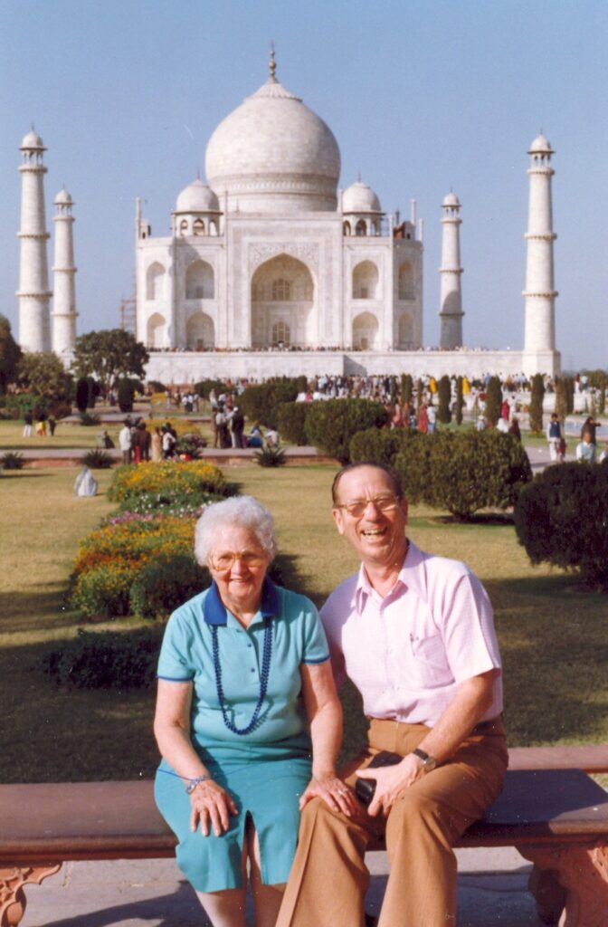 Elderly couple posing for a picture in front of the Taj Mahal.