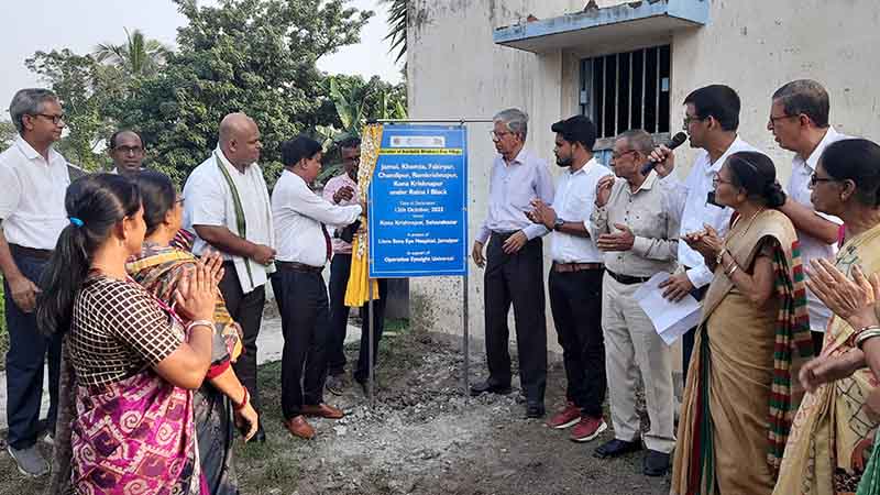 A group of people unveil a sign designating a group of villages as Avoidable Blindness Free. 