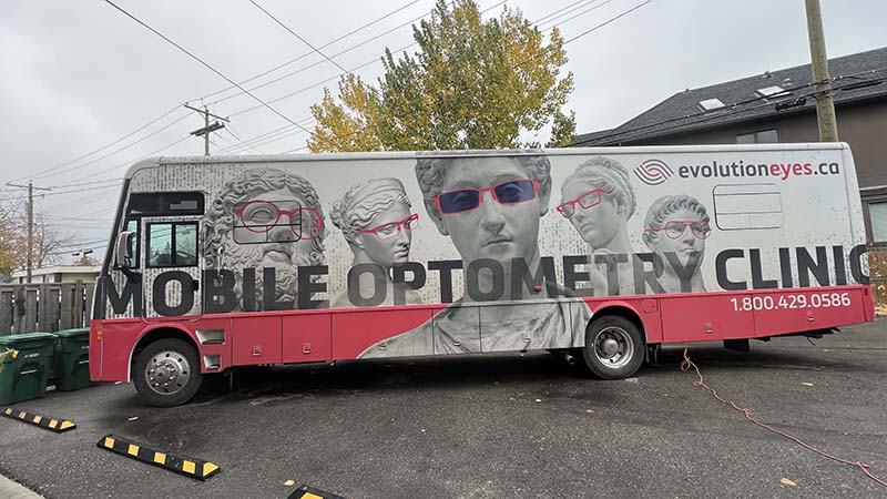 A bus in a parking lot, with the words, 'Mobile Optometry Clinic.'