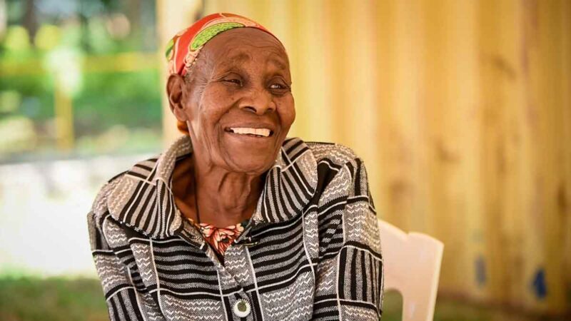 A female senior smiles.|A female senior and a woman stand together outside a brick building.