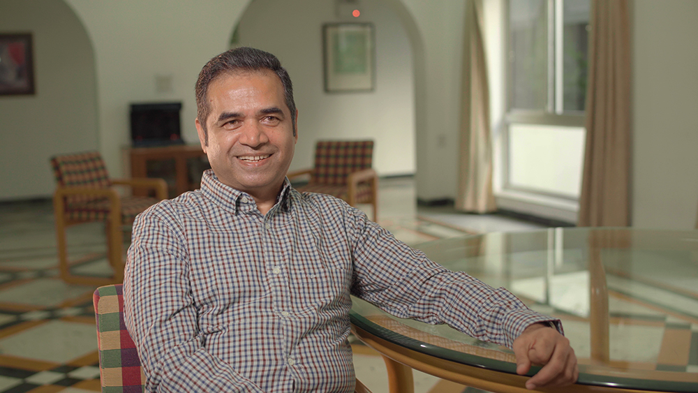 Portrait of Kash|Operation Eyesight's CEO Kash talks to a family at a vision centre